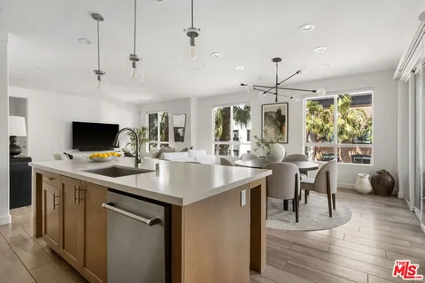 a kitchen with kitchen island a sink counter top space appliances and a living room view
