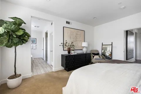 a bedroom with a bed table and a potted plant