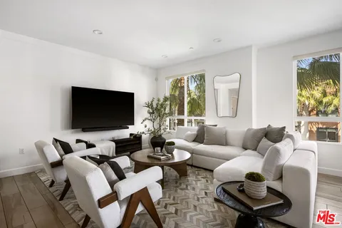 a living room with furniture floor to ceiling window and a flat screen tv