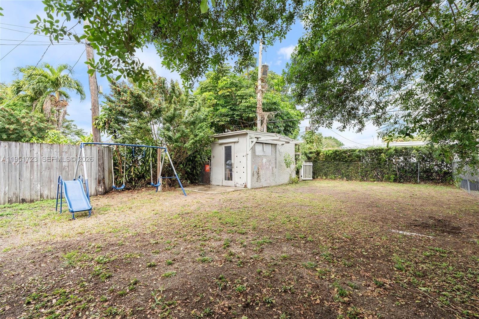 9601-9603 Southwest 36th Street Miami, FL 33165 - Photo 13 of 45 a view of a backyard with a tree and wooden fence