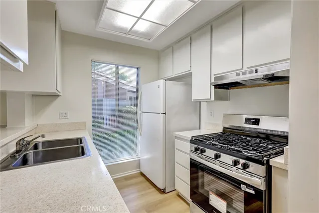 a kitchen with stainless steel appliances granite countertop a stove a refrigerator and a sink with wooden cabinets