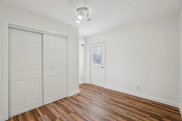 an empty room with wooden floor closet and windows