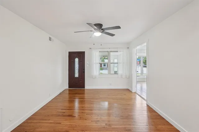 a view of an empty room with window and wooden floor