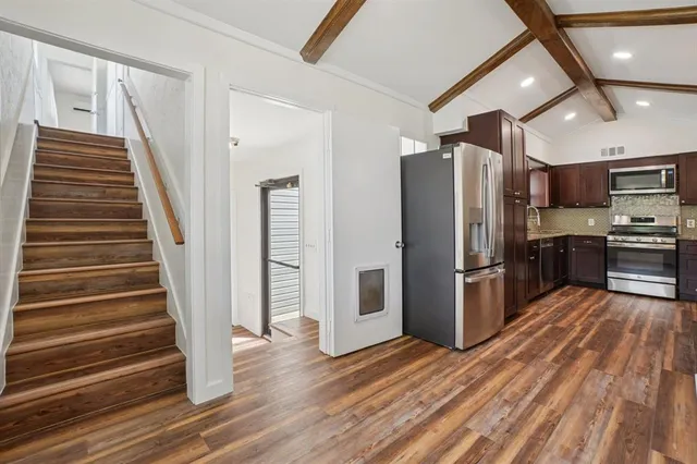 a kitchen with stainless steel appliances a refrigerator and wooden floor