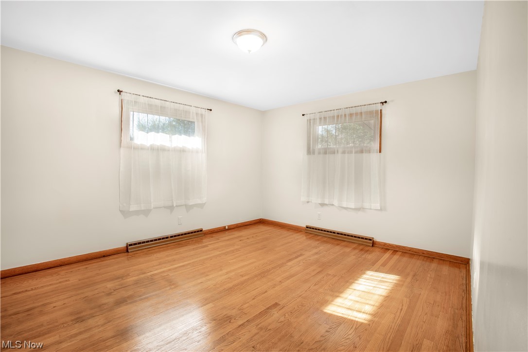 Spare room with baseboard heating and light wood-type flooring