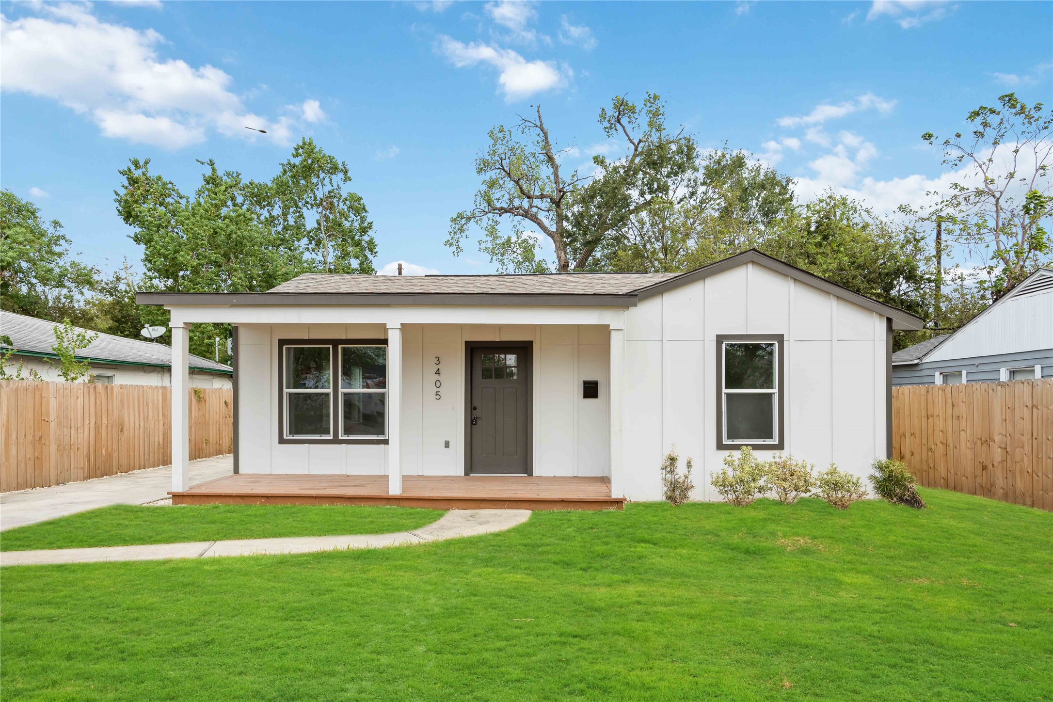 Discover your charming new bungalow, featuring an inviting porch and vibrant green surroundings.