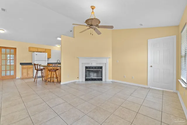 a view of an empty room with chandelier fan and fire place