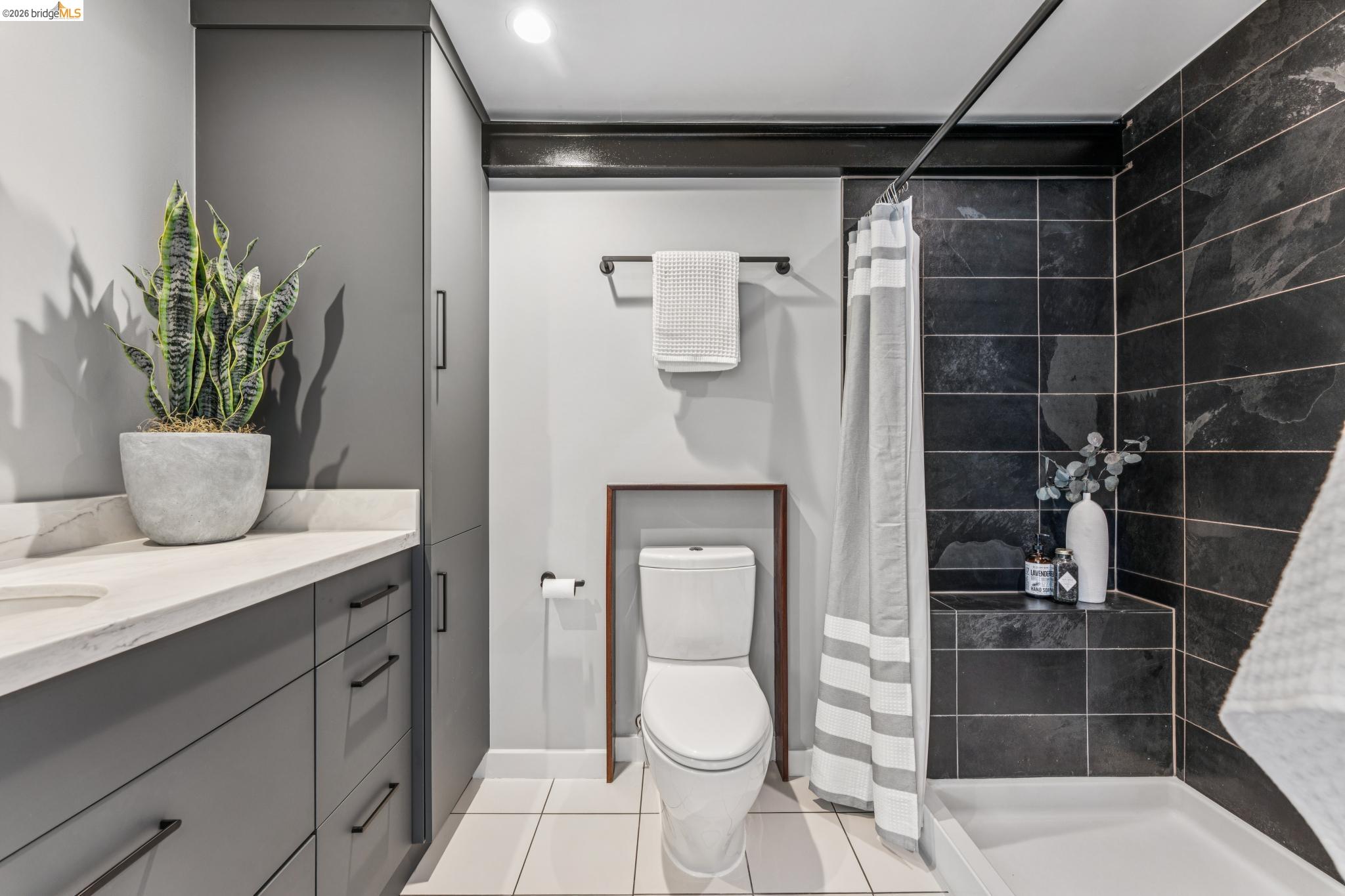 829 21st Street, Unit 1 Oakland, CA 94607 - Photo 31 of 46 a bathroom with a granite countertop sink a toilet and shower