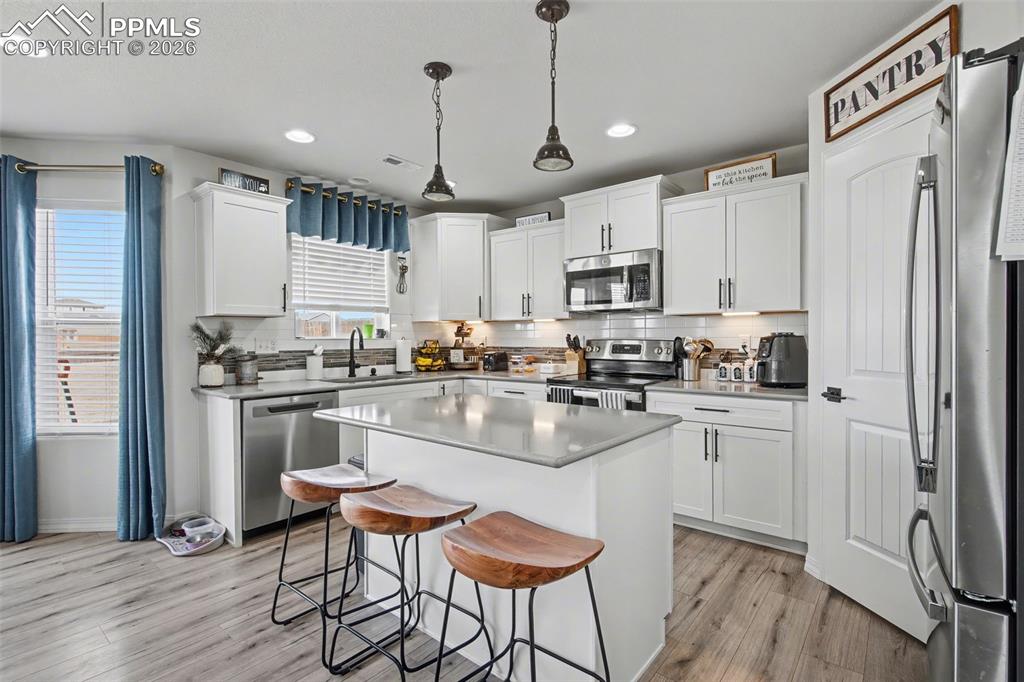 7811 Berwyn Loop Peyton, CO 80831 - Photo 13 of 38 a kitchen with stainless steel appliances granite countertop a refrigerator a stove top oven a sink dishwasher and white cabinets with wooden floor