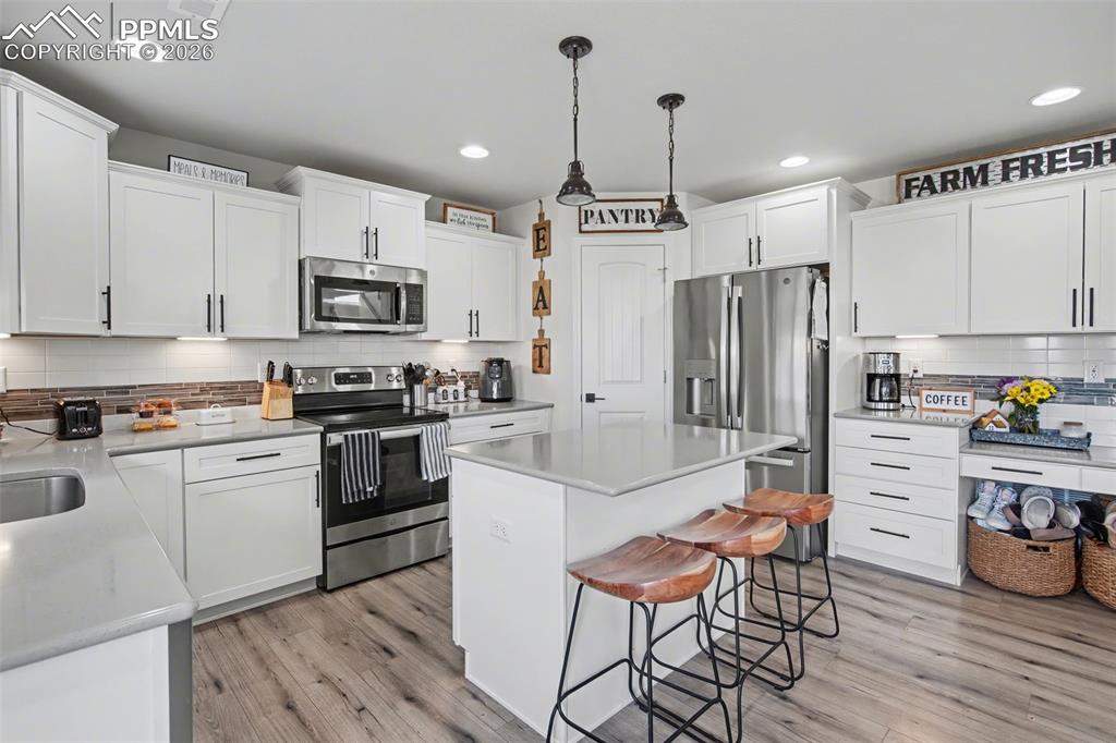 7811 Berwyn Loop Peyton, CO 80831 - Photo 15 of 38 a kitchen with granite countertop a refrigerator stove and white cabinets with wooden floor