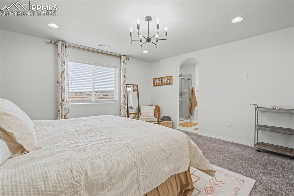 7811 Berwyn Loop Peyton, CO 80831 - Photo 25 of 38 a bedroom with a bed and a chandelier
