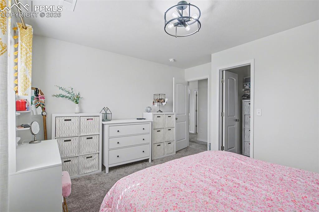 7811 Berwyn Loop Peyton, CO 80831 - Photo 35 of 38 a bedroom with a bed and a chandelier