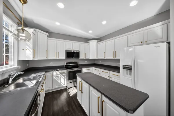 a kitchen with granite countertop white cabinets sink and stainless steel appliances