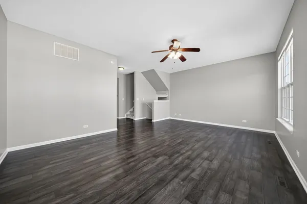 a view of empty room with wooden floor and fan