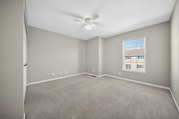 an empty room with a ceiling fan and window