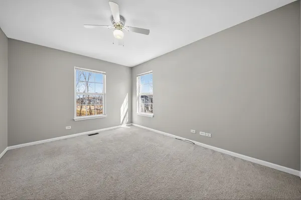 an empty room with windows and ceiling fan