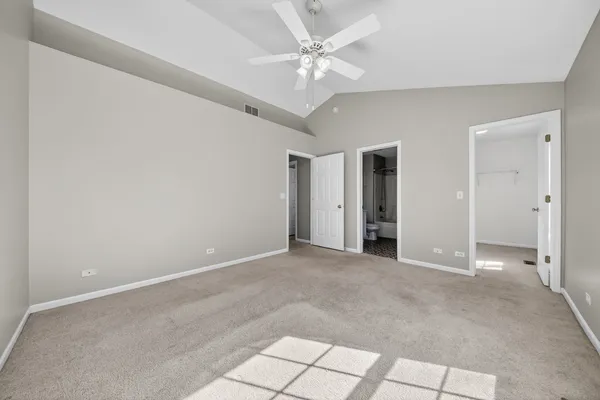 an empty room with windows and chandelier fan