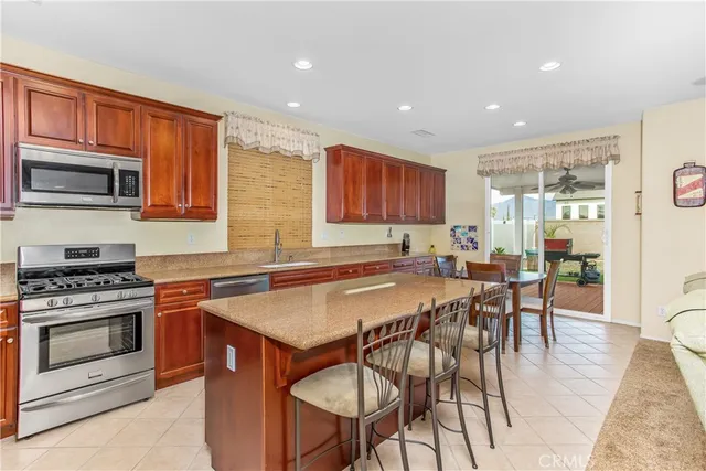 a kitchen with stainless steel appliances granite countertop a stove a sink a microwave a dining table and chairs with wooden floor