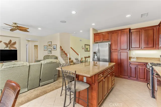 a dining hall with stainless steel appliances granite countertop a refrigerator a sink dishwasher a dining table and chairs with wooden floor