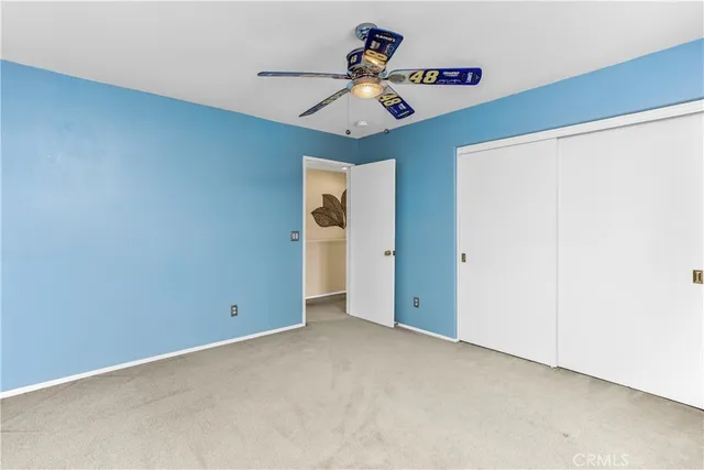 an empty room with a ceiling fan and carpet