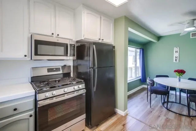 a kitchen with stainless steel appliances white cabinets and stove top oven