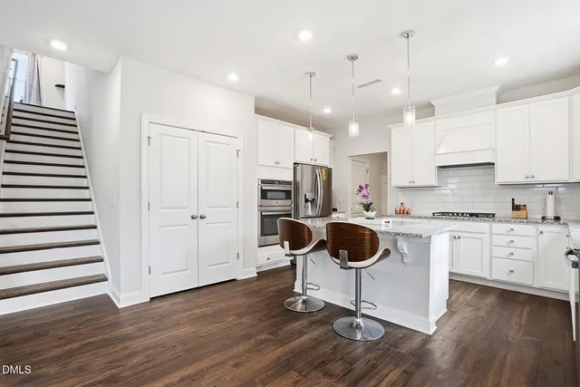 a kitchen with kitchen island white cabinets and stainless steel appliances