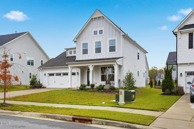 a view of a white house with a swimming pool lawn chairs and a yard