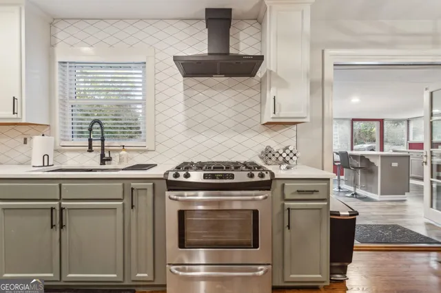 a kitchen with stainless steel appliances a stove a sink and white cabinets