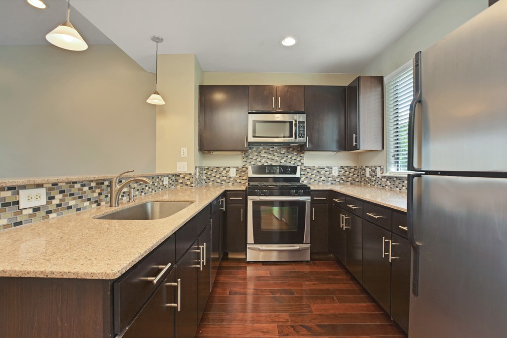 a kitchen with kitchen island granite countertop a sink stove and refrigerator