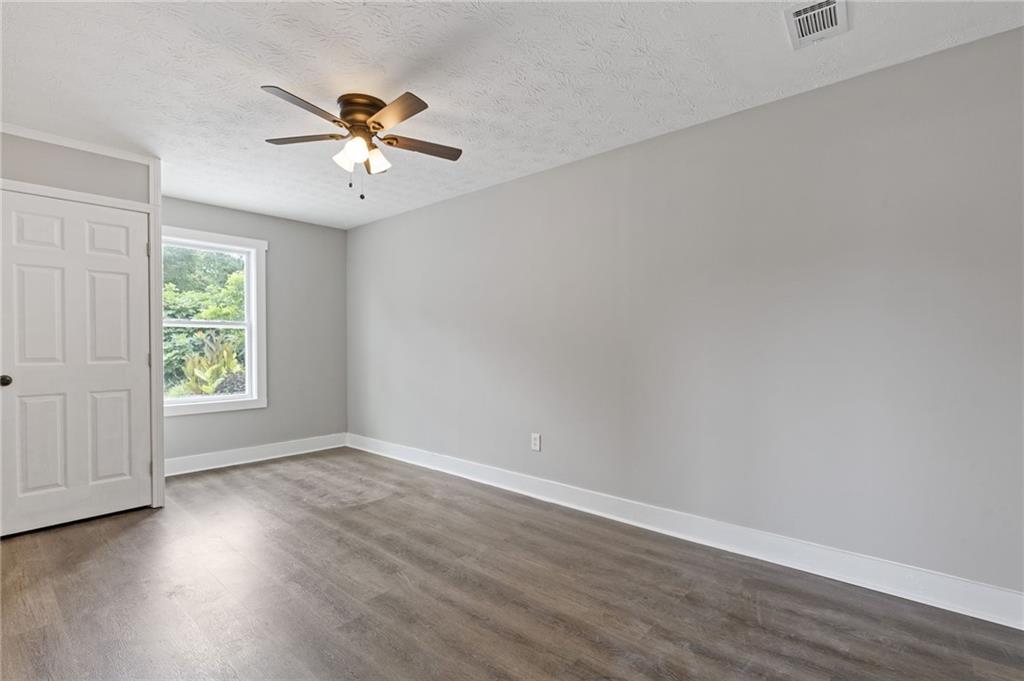 1164 Red Oak Cove Tucker, GA 30084 - Photo 6 of 24 an empty room with wooden floor chandelier fan and windows