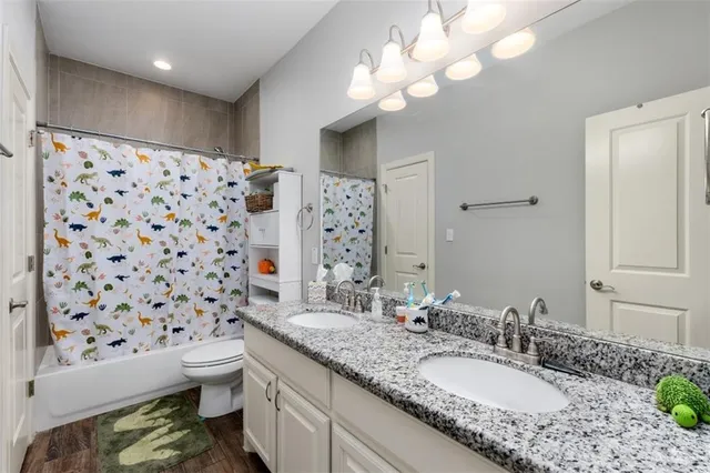 a bathroom with a granite countertop double vanity sink mirror and toilet