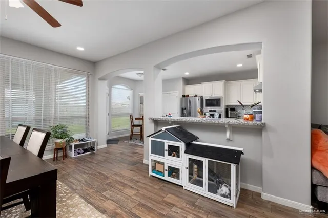 a living room with stainless steel appliances kitchen island granite countertop a table chairs and a refrigerator