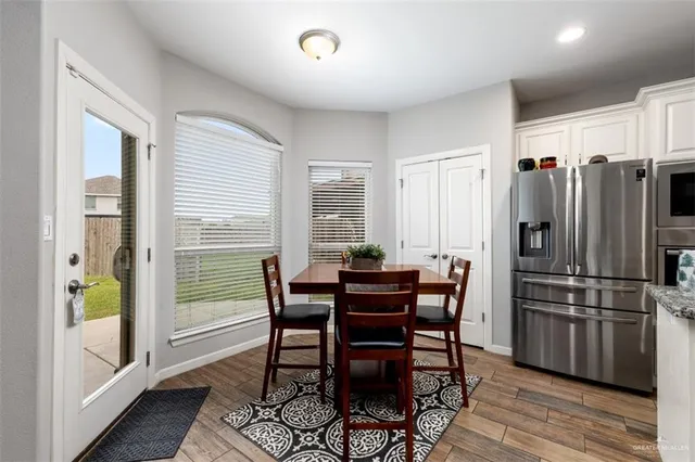 a kitchen with stainless steel appliances a dining table chairs and refrigerator