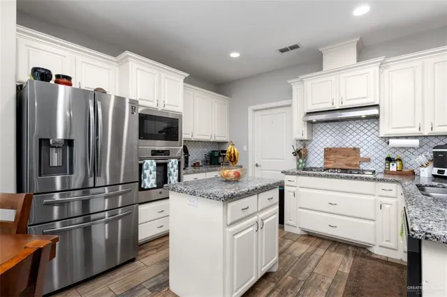 a kitchen with stainless steel appliances granite countertop a refrigerator stove and sink