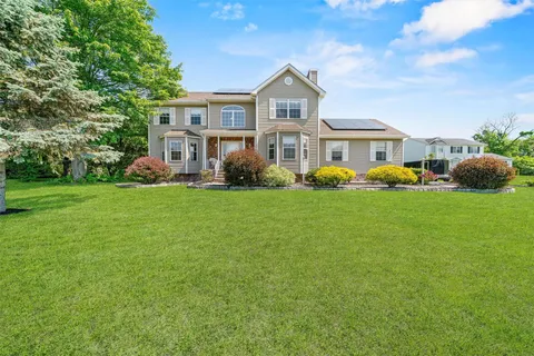 a front view of a house with a garden and trees