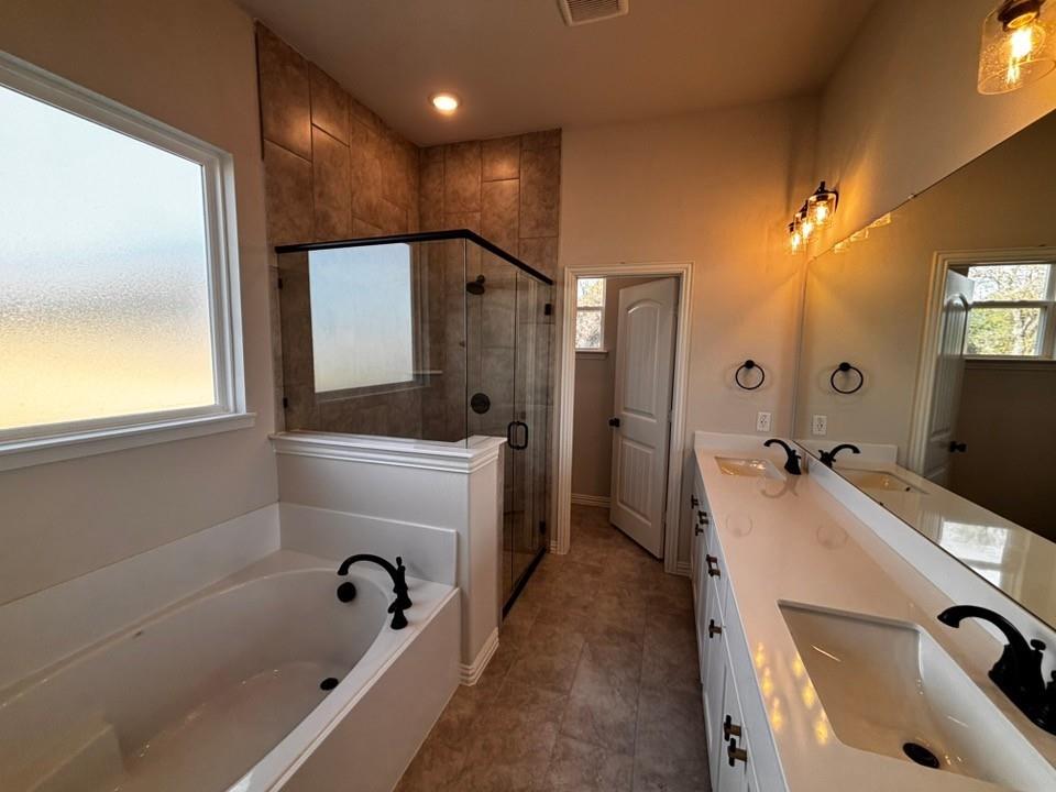 108 Pheasant Run Drive Rhome, TX 76078 - Photo 8 of 14 Dual vanity with integrated sinks, a built-in soaking tub, a tiled shower with glass enclosure, and modern black fixtures