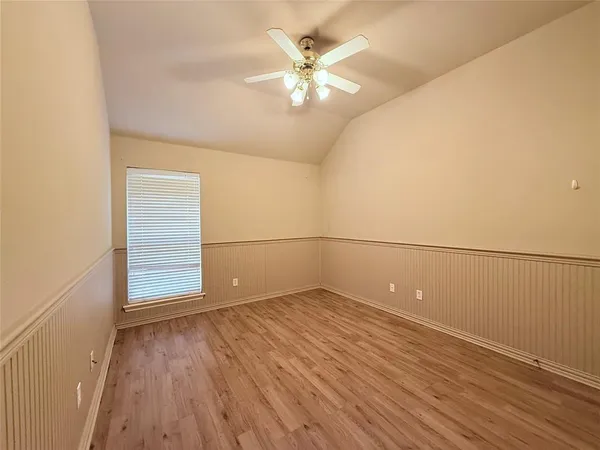 an empty room with wooden floor fan and windows