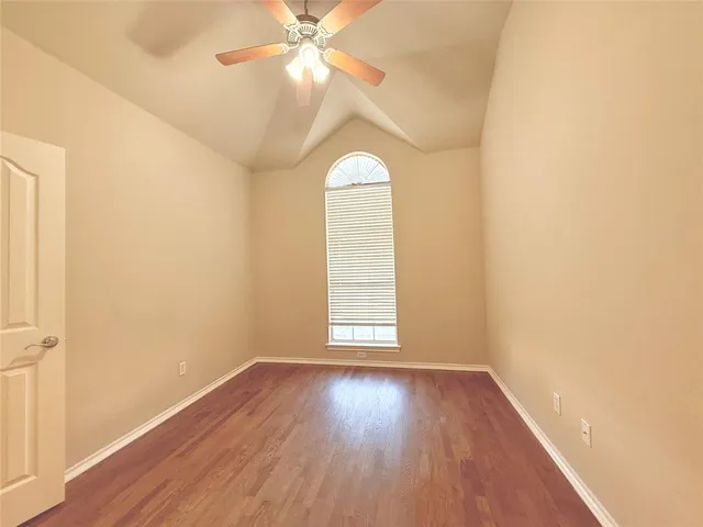 an empty room with wooden floor fan and windows