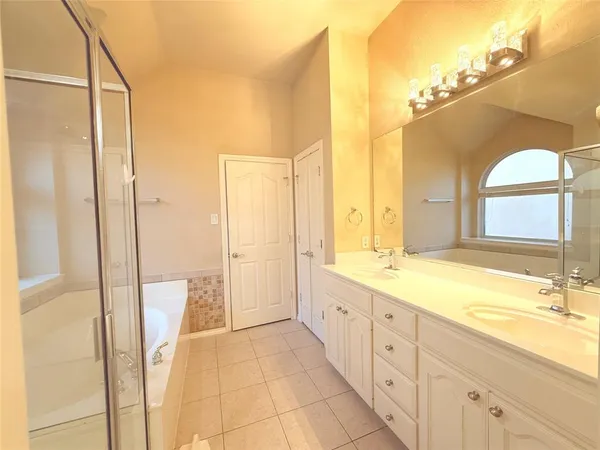 a bathroom with a double vanity sink and mirror with bathtub