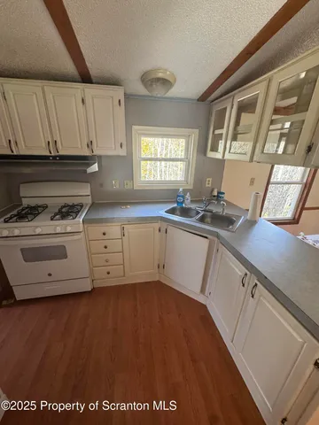 a view of a kitchen with stainless steel appliances wooden floor and cabinets