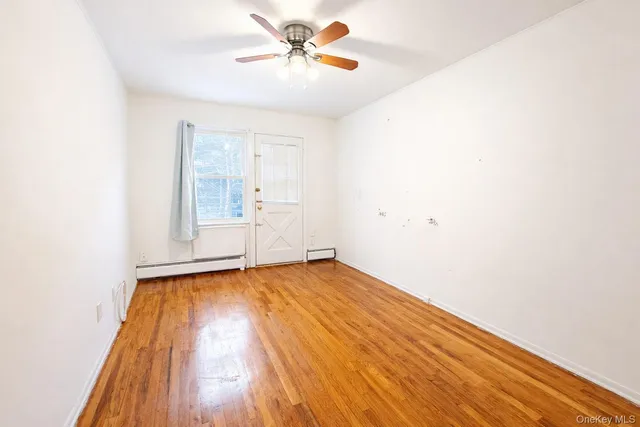 a view of an empty room with window and a ceiling fan