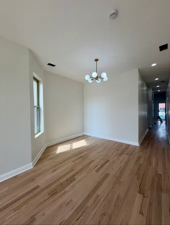 a view of empty room with wooden floor and chandelier