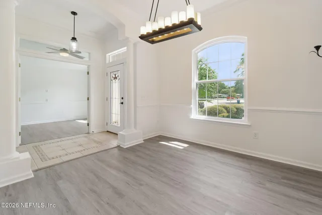 an empty room with wooden floor windows and a chandelier