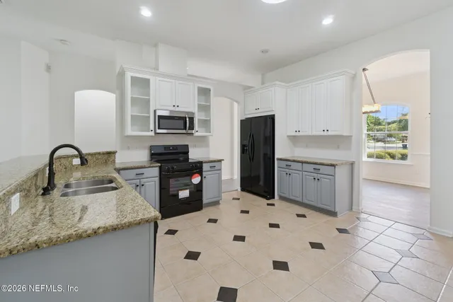 a kitchen with granite countertop a refrigerator and a stove top oven