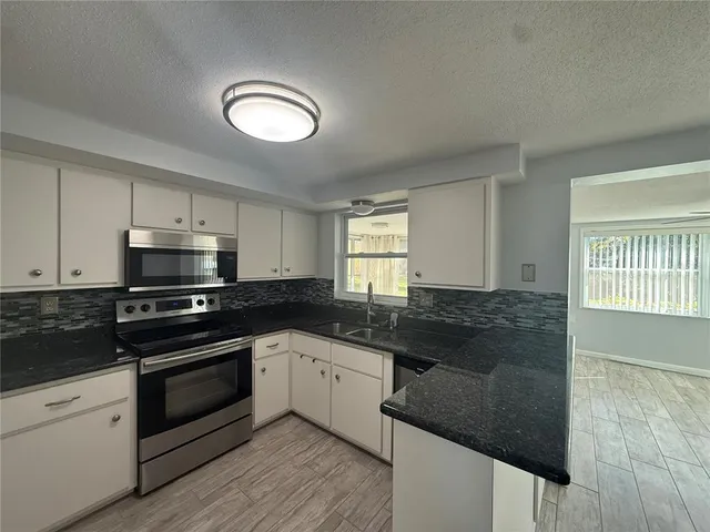 a kitchen with granite countertop a stove sink and cabinets
