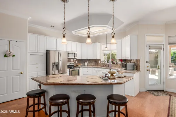 a kitchen with stainless steel appliances granite countertop a dining table chairs refrigerator and cabinets