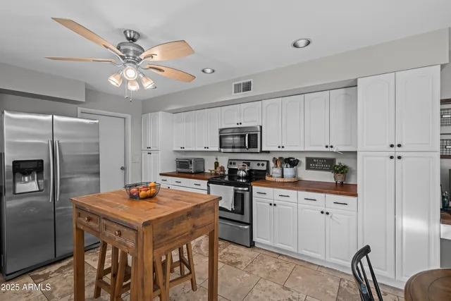 a kitchen with stainless steel appliances a sink a stove a refrigerator cabinets and chairs