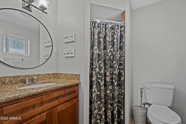 a bathroom with a granite countertop toilet sink and mirror