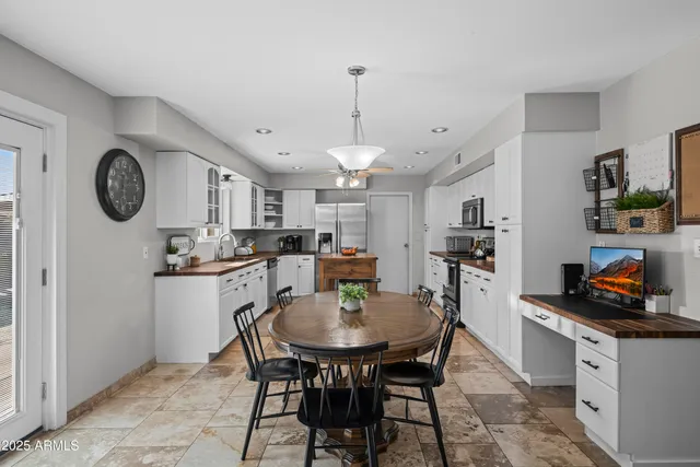a kitchen with stainless steel appliances granite countertop a dining table chairs stove and cabinets