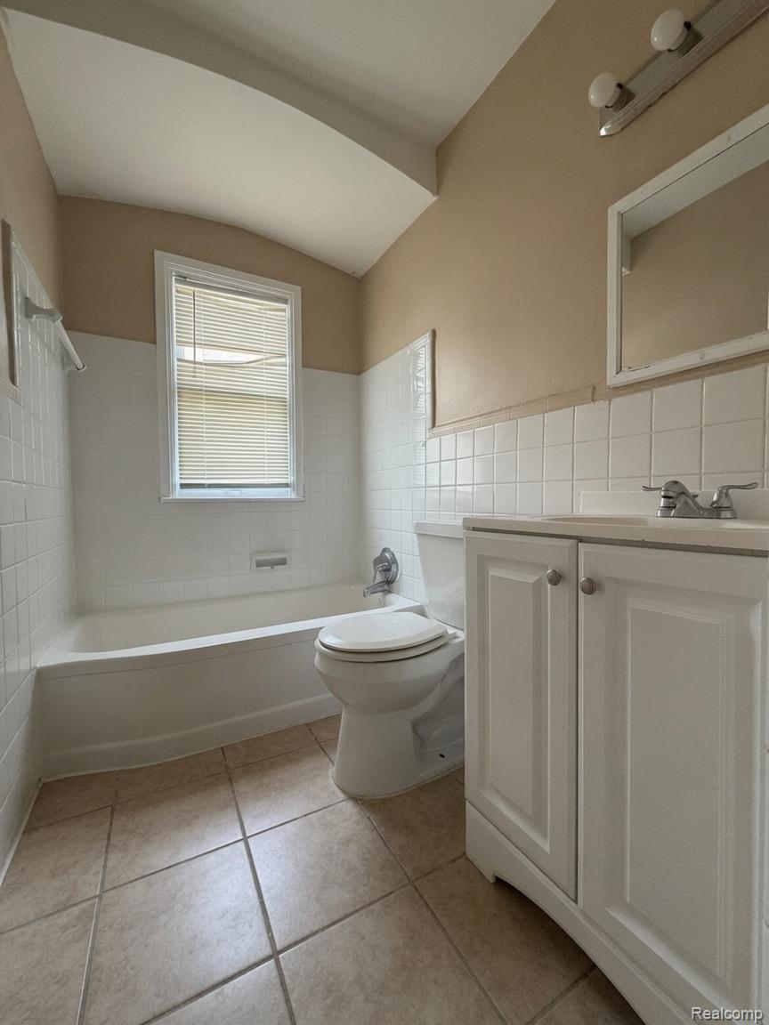 7286 Faust Avenue Detroit, MI 48228 - Photo 14 of 19 Bathroom featuring a white bathtub, ceramic tile flooring, a window with blinds, a vanity with white cabinetry, and a wall-mounted light fixture